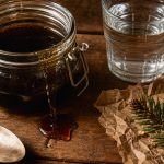 Miel de sapin bienfaits, filet sombre de miellat sur table en bois avec résine de sapin
